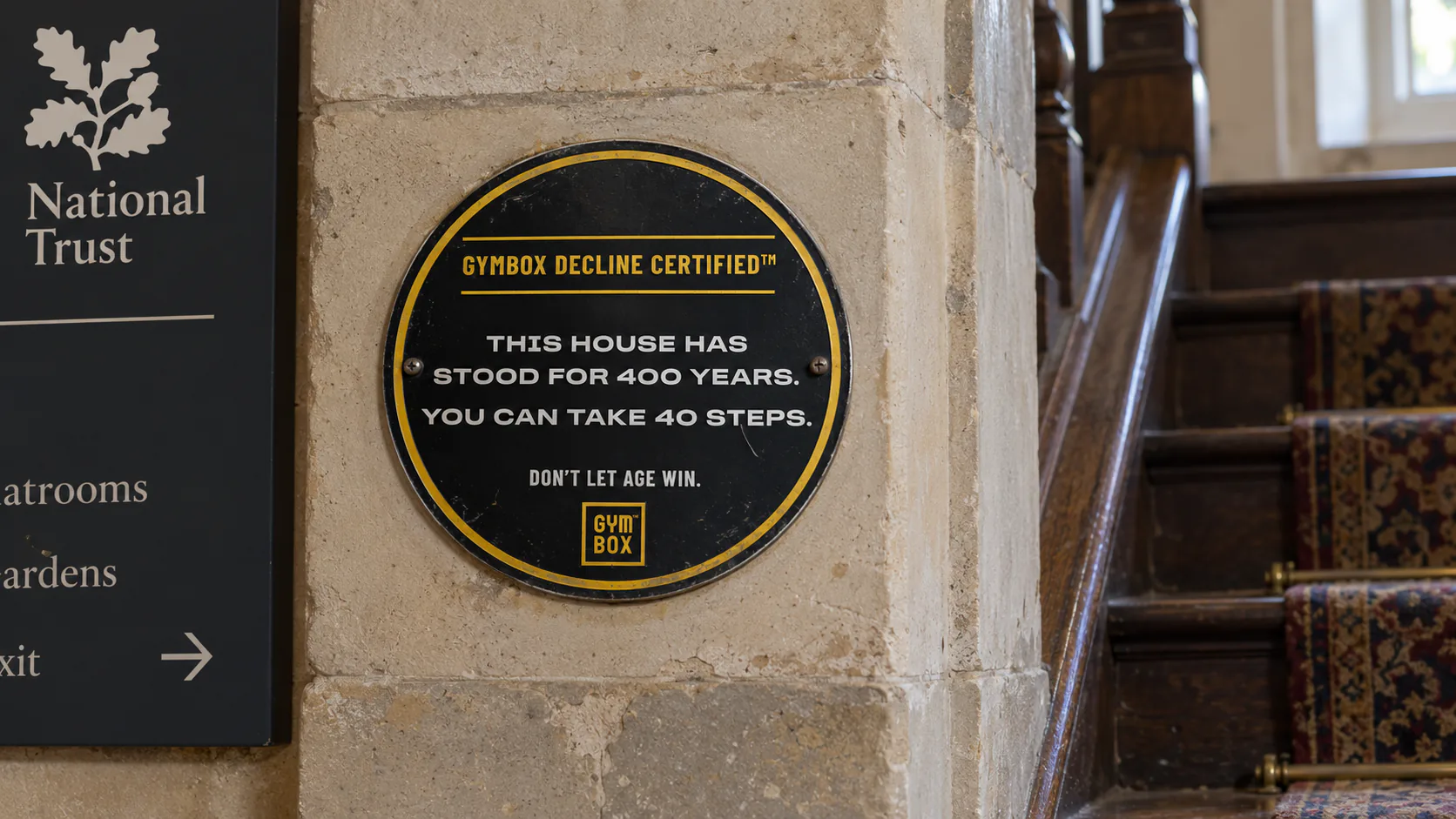 Gymbox Decline Certified plaque by a National Trust staircase: This house has stood for 400 years. You can take 40 steps.